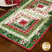 An angled shot of the table runner on the set wooden table with place settings, showcasing the log cabin piecing.