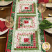 A shot of the table runner set with coordinating decor, glasses, place settings, and cloth napkins.
