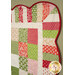 An angled super close up on the upper right corner of the quilt, demonstrating details on the fabric colors and scalloped border.