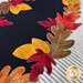 A super close up on the wool appliqué leaves of the mat, demonstrating the vibrant dyes and embroidered details.