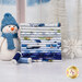 A stack of the fabrics included in the Let it Snow-Man! collection with snow and trees and a window and a snowflake and a plush snowman and thread.