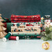 A stack of the fabrics included in the Gifts of Gratitude collection with a golden tree and a present and mistletoe and a snowman and thread.
