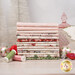A stack of the fabrics included in the Christmas Magic collection, with trees and ornaments and a glass container and a pointsettia.