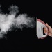 A model holds the iron and demonstrates the steam function on a black background.