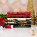 A stack of the fabrics included in the Merry Christmas 2026 collection, with trees and a garland and a poinsettia and thread.