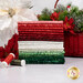 A stack of the fabrics included in the Tonga Poinsettia collection, with a basket and poinsettias and pine branches and thread.