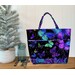 A Playing with Panels Market Tote colored in black, purple, green, and electric blue butterfly fabric, staged with coordinating decor.
