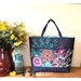 A Playing with Panels Market Tote colored in navy, pink, and teal floral fabric, staged with coordinating decor.