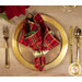 A top down shot of a place setting with the reversible red and green plaid fabric of the napkin faced out.