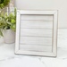 The fully assembled and painted Spring Comes Again Shiplap Frame Cross Stitch Display, staged on a white tabletop.