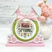 The fully assembled and painted Bunny Round Cross Stitch Display Frame, staged on a white tabletop next to a vase of pink roses, displaying a festive cross-stitch project.