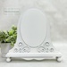 The fully assembled and painted Fleur Oval Cross Stitch Frame, staged on a white tabletop.