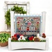 The fully assembled and painted Picket Perch Displays, staged on a white tabletop with coordinating greenery, displaying a patriotic cross-stitch project.