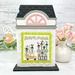 The fully assembled and painted City Flower Shop Cross Stitch Display Backer, staged on a marble countertop with coordinating flowers, displaying a spring cross-stitch project.