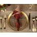 A top down shot of a place setting with the reversible red fabric of the napkin faced out.