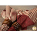 A shot of the four red and striped reversible cloth napkins in wooden napkin holders, spread across a wooden table.