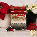 A stack of the fabrics included in the Poinsettia Radiance collection with pots and poinsettias and thread.