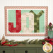 The completed Patchwork Holiday Joy project colored in red, cream, green, and aqua fabrics from the Sugarberry collection by Andover Fabrics, hung on a white paneled wall and staged with coordinating Christmas decor and foliage.