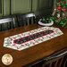 The completed Easy Striped Table Runner colored in red, white, and black fabrics from the Merry Gnome-ments collection by Wilmington Prints, staged on a wood table.
