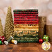A stack of the fabrics included in the Holiday Follies Collection, with gold trees and candles and ornaments and thread.
