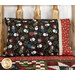 The Magic Pillowcase in black and red snowman fabrics from the Holly Jolly Flannel collection, staged on a bed with a matching patchwork quilt in a cabin setting.