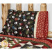An angled shot of the Magic Pillowcase in black and red snowman fabrics from the Holly Jolly Flannel collection, staged on a bed with a matching patchwork quilt in a cabin setting.