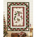 The completed Ribbon Border Panel Quilt colored in red, green, and cream fabrics from the Woodland Snowmen collection by Wilmington Prints, hung on a white paneled wall and staged with a decorated tree and cozy coordinating décor.