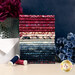 A stack of the fabrics included in the Missing You Fat Quarter Bundle, with flowers and a vase and an envelope and thread.