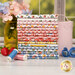 A stack of the fabrics included in the Homegrown Preserves collection, with a window and jars and flowers and strawberries and thread.