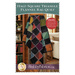 Front cover of the pattern showing the completed quilt in contrasting black and rainbow colored flannel fabrics, draped on a quilt ladder in a cozy cabin scene.