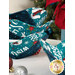 A stylized close up on the bowl cozies on the white table, showing off details on the teal and navy fabrics; a red poinsettia peeks into frame from the upper right corner.