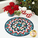 The completed Point of View Kaleidoscope Folded Star Table Topper colored in teal, white, and blue fabrics from the Woodland Wishes collection, staged on a white table with coordinating winter décor.