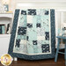 The Easy as ABC and 123 Crib Quilt featuring a patchwork design in winter flannel fabrics like blue, navy blue, teal and white, artfully draped over a white crib next to a stuffed polar bear wearing a teal scarf and coordinating decor.