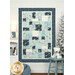 The Easy as ABC and 123 Crib Quilt featuring a patchwork design in winter flannel fabrics like blue, navy blue, teal and white, hanging from a white paneled wall next to a frosted tree and coordinating decor.