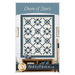Front cover of the Chain of Stars pattern, showing the completed quilt colored in blue fabrics from the Sacre Bleu collection and cream fabrics from the Itty Bitty Backgrounds collection, staged on a white shiplap wall and staged with coordinating furniture and décor.