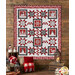 The completed Blizzard Fun Quilt, colored in gray, red, and black fabrics from the Blizzard Fun collection by Henry Glass Fabrics, staged on a rustic wood cabin wall with coordinating pillows and décor.
