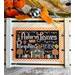 A framed cross-stitch art piece with the text Autumn Leaves and Pumpkins Please, featuring pumpkins and a house design, set against a rustic background with decorative elements.