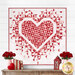 The completed Mini Exploding Heart quilt colored in red, pink, and white fabrics from the Letters to Cupid collection, hung on a white paneled wall above a wooden dresser; coordinated pink and red décor adorn the table. 