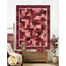The completed Easy as ABC and 123 quilt finished in pink and maroon fabrics from the operetta collection, hung on a white paneled wall and surrounded by coordinating décor. 