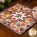 A stylized shot of the square hot pad, demonstrating details on the cream and orange fabrics.