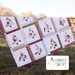 Image of the finished quilt hanging on a fence in a sunlit field and the Emmitt and Ivy Logo