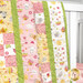 A close up shot of the Patchwork Baby Quilt kit draped over a crib. 