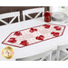The completed Foundation Paper Piecing Hearts Table Runner, colored in red and white fabrics from the Redberry Lane collection by Henry Glass Fabrics, staged on a wooden dining table with white chairs in a bright kitchen.