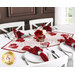 The runner  staged on a wooden dining table with white chairs in a bright kitchen, complemented with four coordinating table settings of plates, cutlery, and red napkins.