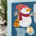 A super close up on the snowman, showing details on the fabrics, prints, and hand-embroidered finishing touches.