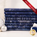 A stack of the eight fabrics included in the 8 HY Bundle Dark Blue/Silver by Stof Fabrics, staged with thread and ornaments.
