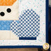 A close up on the lower right corner of the project, showcasing the snowman's glove and the binding, with coordinating holiday décor in the background.