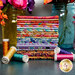 A stack of the fabrics included in the Kaffe Fassett From the Archives FQ bundle, with flowers and jars and thread.