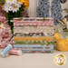 A stack of the fabrics included in the My Secret Garden Fat Quarter set, placed in front of the panel from the same collection, with flowers and a jar and a bird and a butterfly and thread.