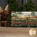 A stack of the fabrics included in the Northwoods Lodge Cuddle collection, with a moose and pine trees and pinecones.